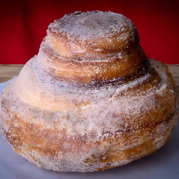 A House of Bagels cinnamon roll, generously coated with powdered sugar, against a red background.