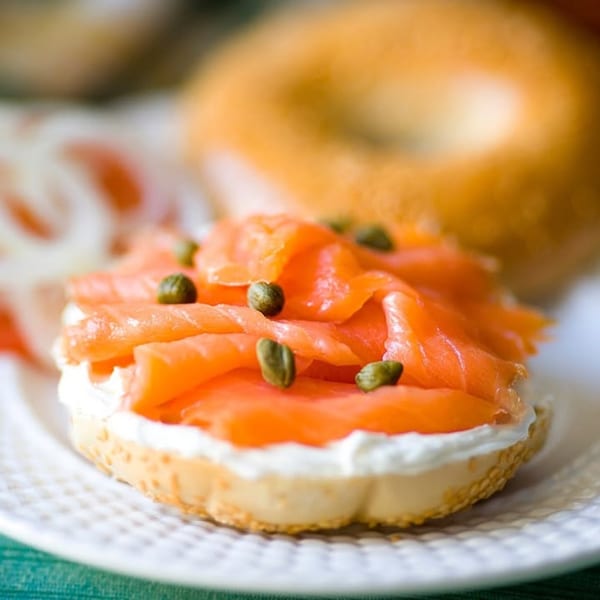 House of Bagels' bagel with cream cheese, smoked salmon, and capers on a white plate.